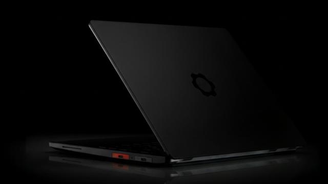 Photo of the Framework Pro taken from their blog post about the launch. It is viewed from one of the rear corners with the lid partly open. One of the part adapters is translucent orange, which seems to be the signature colour of the model.
