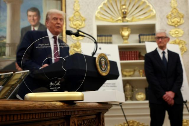 Photo of Tim Apple presenting that engraved glass disc with the golden base to Donald Trump. The disc is foregrounded, with the two men out of focus in the background.